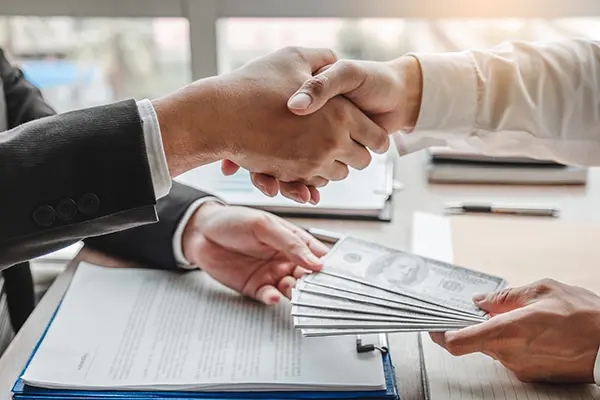 Businessman shaking hands giving dollar bills as a loan